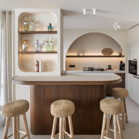 Open keuken met verlichte barnis, afgeronde notelaar toog met natuurstenen blad en boognis, maatwerk van YVES Interieur Op Maat.