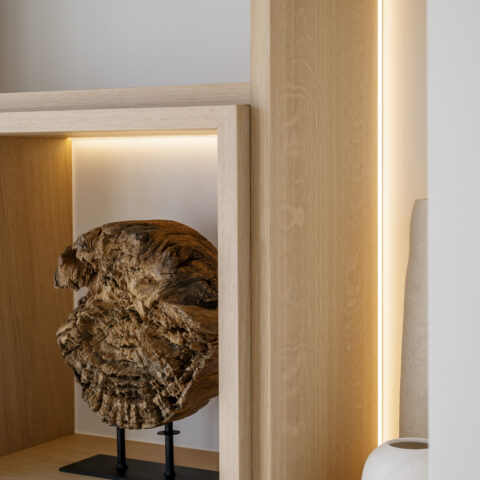 Detail van een eiken wandkast met verlichte nis en verticale ledlijn langs het eikenhout.