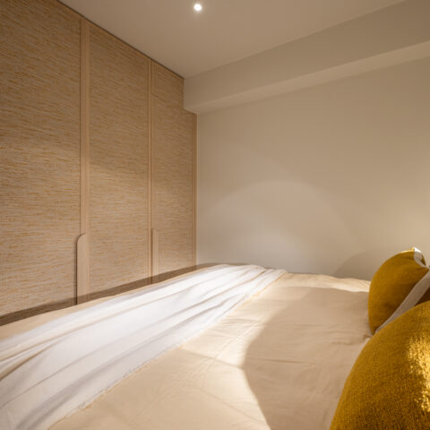 Kastwand met natuurlijke vezelbekleding en eiken omlijsting in de slaapkamer, maatwerk van YVES Interieur Op Maat.