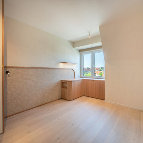 Slaapkamer met wandbekleding in natuurvezel als hoofdbord en een gebogen hoekbureau in eik onder het raam.